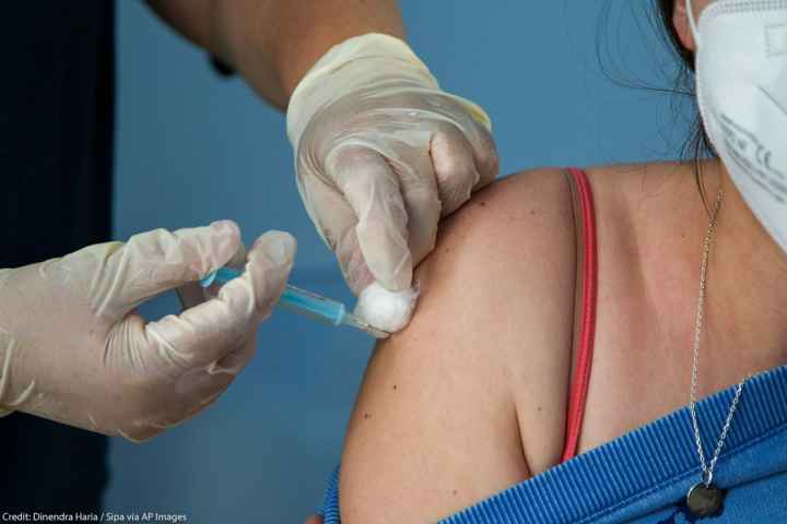 A Covid-19 vaccinator administers the Oxford/AstraZeneca vaccine to a woman at a vaccination centre in London