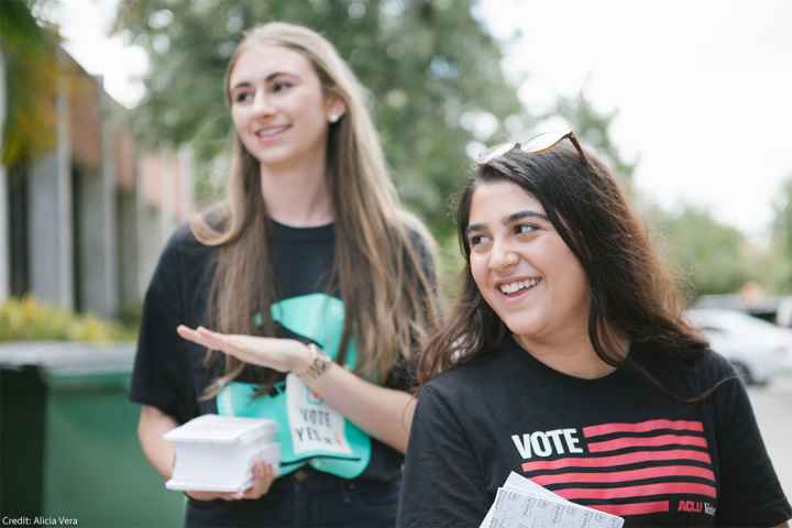 Two smiling canvassers carrying voting information.