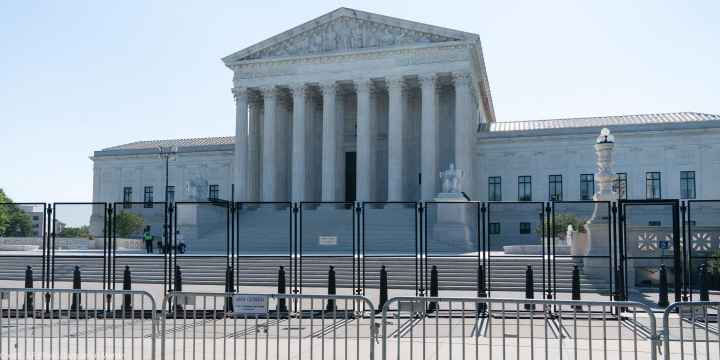 A view front of the U.S. Supreme Court Building behind riot gates.