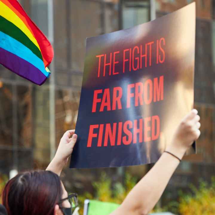 Someone holding a sign that says The Fight Is Far From Finished.