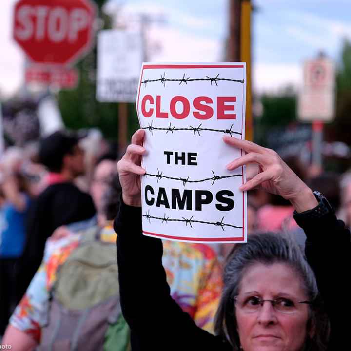 Woman holds sign that reads "Close the Camps" outside of the Immigration and Customs Enforcement (ICE) office in Portland