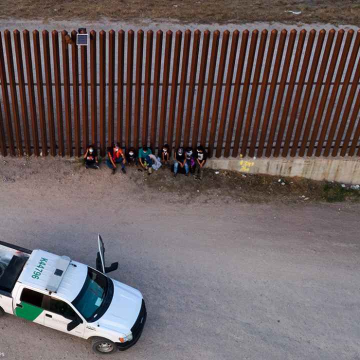 A U.S. Customs and Border Protection vehicle is seen next to migrants after they were detained and taken into custody.