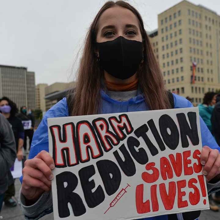 Edmontonian with a sign that reads "harm reduction saves lives," photos of loved ones and crosses with purple ribbons and hearts gather for International Overdose Awareness Day at Capital Plaza outside the Federal Building.