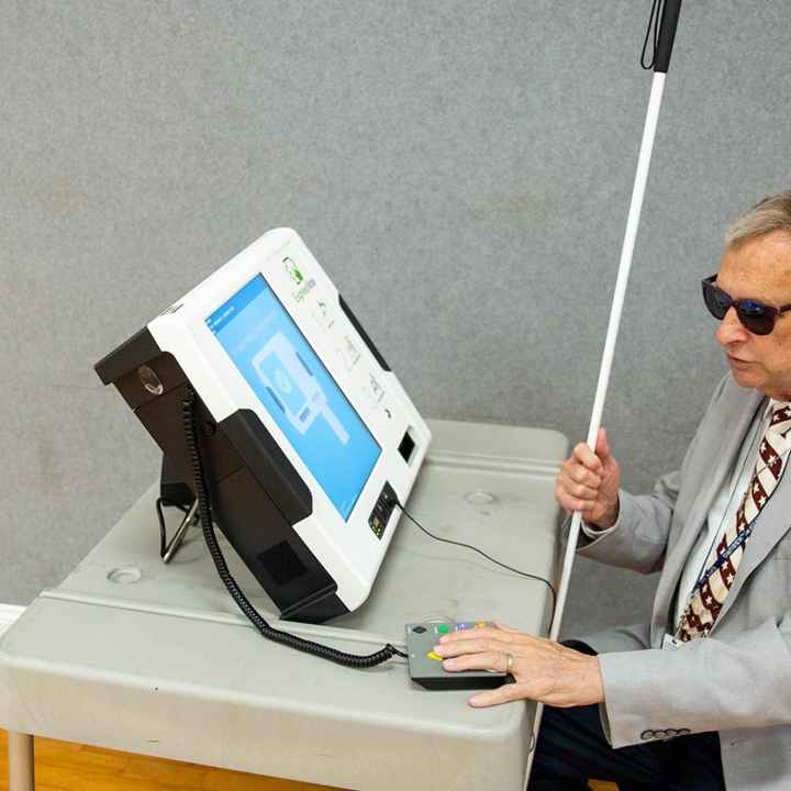 Michael Kasey, who is blind, demonstrates a voting machine that allows people with disabilities to vote.