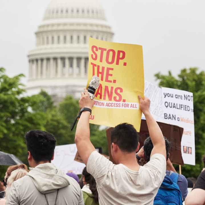 A group of people holding reproductive rights signs in front of the Capitol Building.