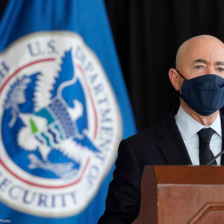 Secretary of Homeland Security Alejandro Mayorkas speaks during news conference with a U.S. Homeland Security flag behind him.