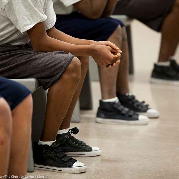 Four children (with faces hidden) sitting inside a detention center.