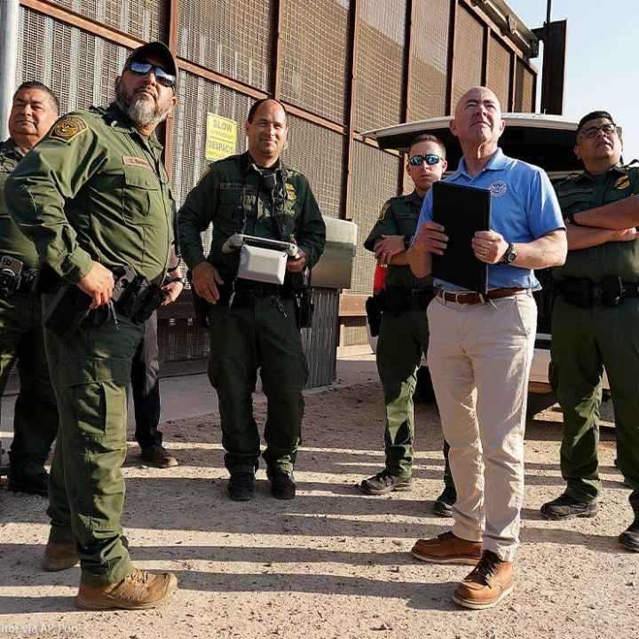 Homeland Security Secretary Alejandro Mayorkas, second from right, looks up along with U.S Border Patrol agents as a drone flies overhead as he tours a section of the border wall Tuesday, May 17, 2022, in Hidalgo, Texas.