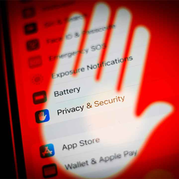 A cellphone screen with its privacy and security settings covered by a transparent hand with a red background.