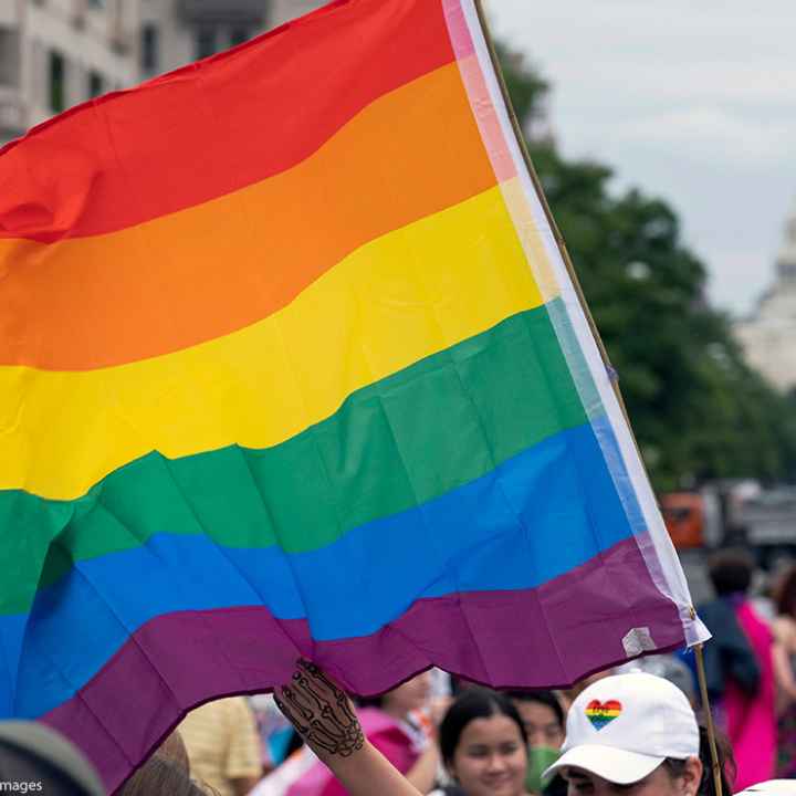 A rainbow flag with the U.S. capitol in the background.