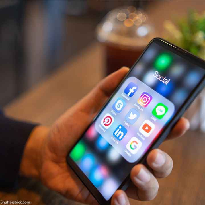 Man holding iPhone with social media icons displayed on the screen