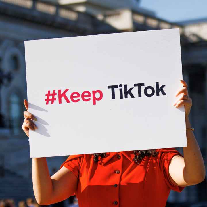 A person is holding a sign outside the Capitol Building that reads " #Keep TikTok".