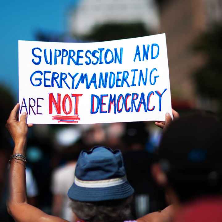 A demonstrator at the March On for Voting Rights in Washington D.C. holds up a sign reading "Suppression and Gerrymandering are Not Democracy".